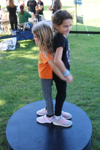 Two girls chat together near a festival booth.