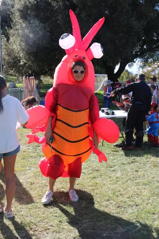A kid grins from inside a giant inflatable lobster costume.
