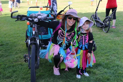 A woman and two children in skeleton costumes and colorful tutus smile for the camera.