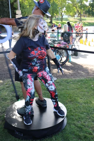 A man in blue flame skull makeup gestures beside a woman in matching zombie makeup at the festival.