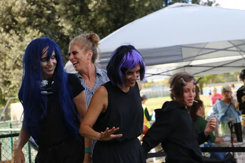 A group in blue wigs poses together and laughs at the festival.