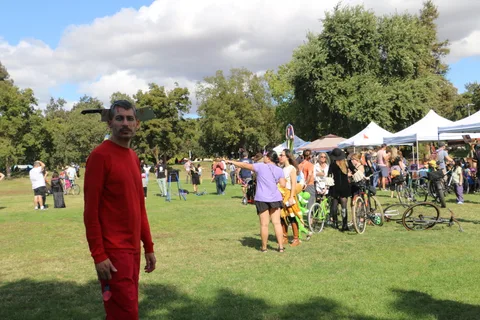 A man in a full red jumpsuit stands alone on the grass.