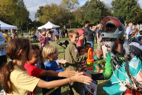 A girl reaches out to high-five a costumed skydiver as other kids wait their turn.