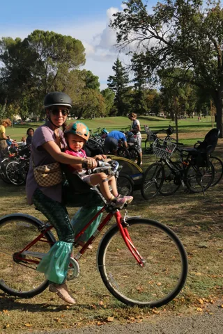 A father and daughter in bike helmets pose together at the parade staging area.