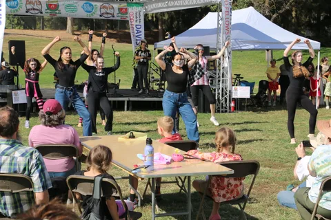 A dance troupe performs on the festival stage beneath a bike event banner.