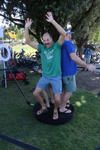 A man raises his arms joyfully under the trees at the festival.