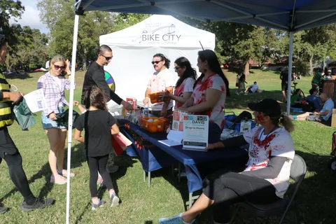 Blood-splattered volunteers run a game booth under a Bike City Theatre Company tent.
