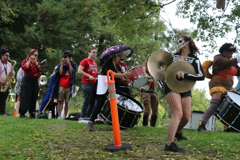 Drummers in skull face paint and fishnets perform in a marching drum line.