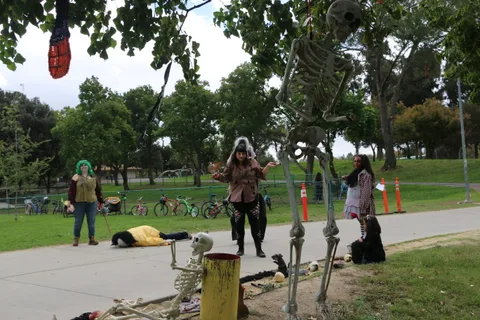 Hanging skeleton decorations sway above the festival path.