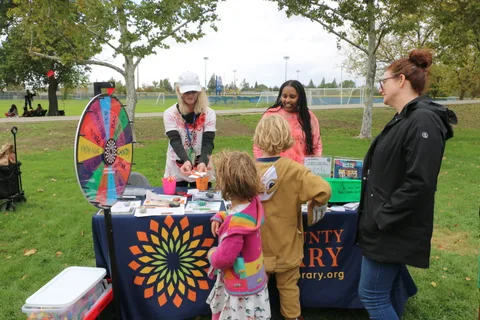 A staff member spins a colorful prize wheel as excited children look on.