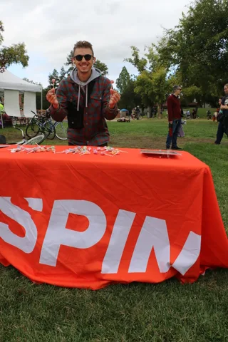 A man smiles with hands raised near a table of treats.