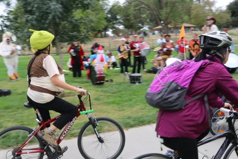 A woman in a purple jacket rides near a couple of children on bikes.