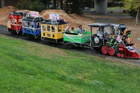 A small Halloween-decorated trackless train sits parked on the roadway.