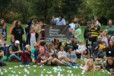 Costumed adults and children including pirates pose together for a group photo.