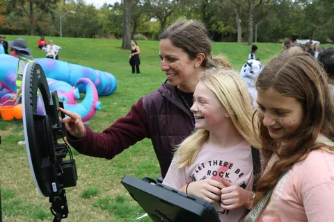 A woman takes a selfie with two smiling girls at the photo booth.