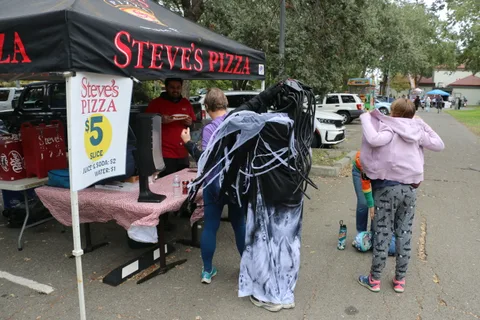 A ghost-costumed figure stands near the Steve's Pizza vendor tent.