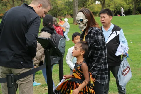 A group of costumed people gather around a camera crew at the festival.