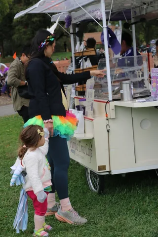 Children stand near a teal cafe cart with a partly visible sign.