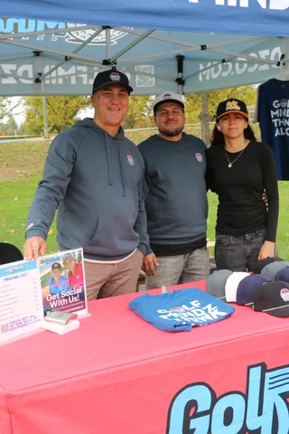 Merchandise and flyers are displayed on a GolfMindz booth table.