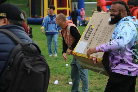 A man carries a large cardboard box through the crowd, his face hidden behind it.
