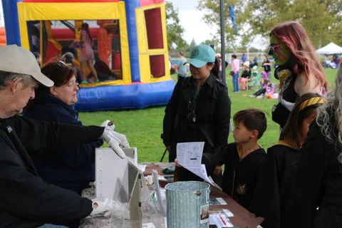 A volunteer hands something to a child across a booth table.