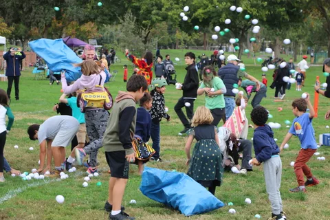 Costumed kids throw white balls into the air in a chaotic, joyful toss.