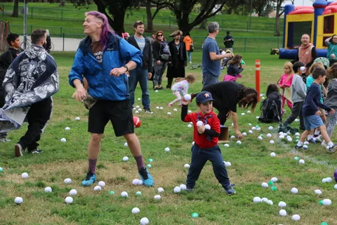 A man reaches for a ball beside a boy in a red shirt amid scattered balls.