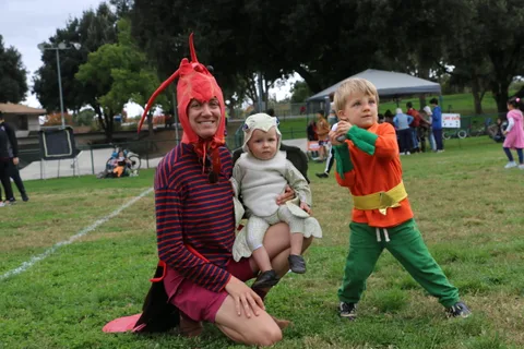 A family in costume, including a lobster hat and a lamb outfit, pose together.