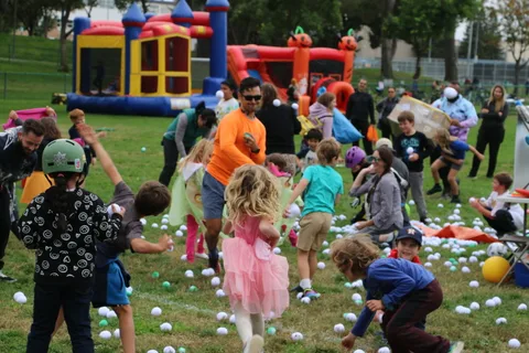 Kids run and play near the bounce houses amid scattered balls.