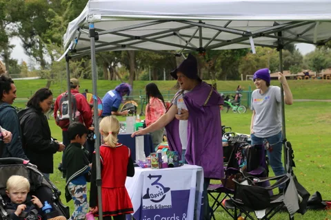 Volunteers in purple robes hand out treats to children at a festival booth.