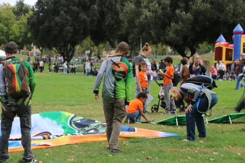 A colorful painted tapestry banner is unrolled on the grass as people gather around.