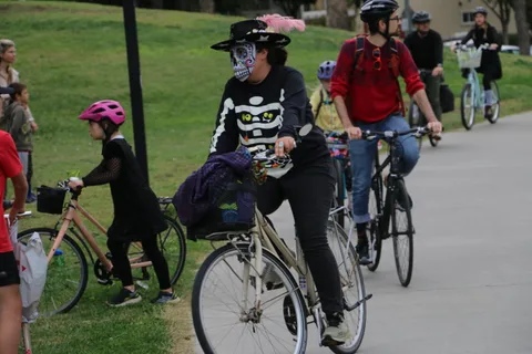 A mixed-age group of cyclists rides together, including a child with a backpack.