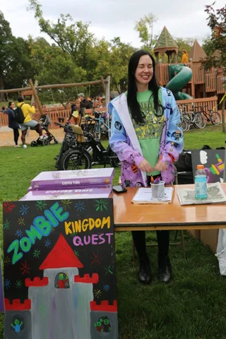 A woman in a colorful costume smiles while walking through the park.