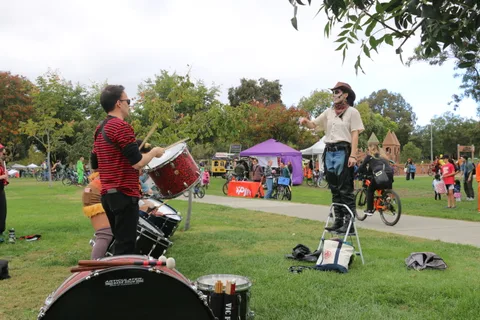 A drummer performs solo with his drum set on the grass.