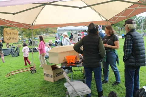 Festival-goers gather near a coffin-shaped prop under a tent.