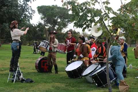 A costumed drum corps performs with an inflatable chicken among the players.