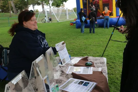 Volunteers staff an informational booth table in the park.