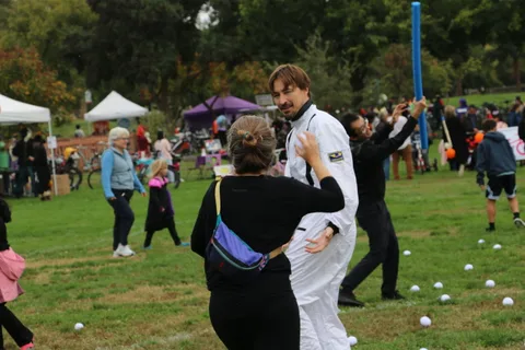 Two festival-goers talk near the purple tents in the background.