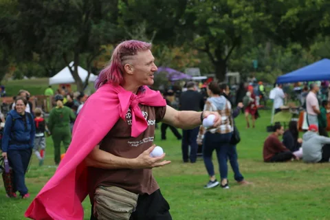 A man in a pink cape gestures during the festival lawn game.