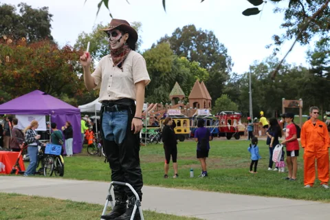 A man in skeleton face paint raises a drumstick playfully.