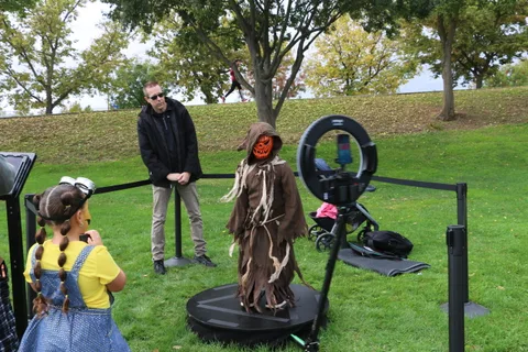 A man stands near the 360 photo booth as a costumed woman waits.