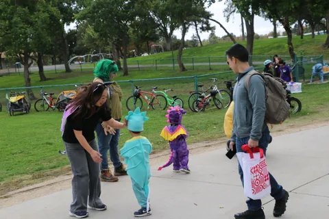 A performer crouches near costumed children as a man walks past.