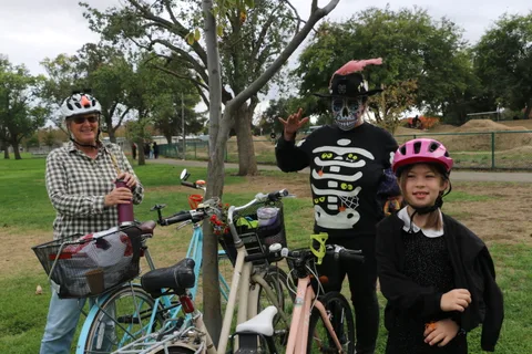 A group including a man with a painted skull face stands near bicycles.