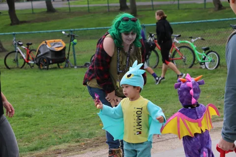 A costumed performer poses with two children dressed as a dragon and a dinosaur.