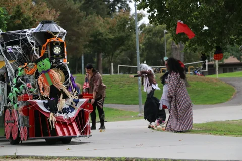 A green zombie figure and orange garland decorate the front of a Halloween parade train.