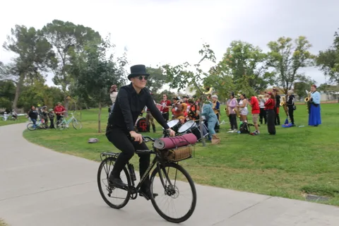 A man in a bowler hat rides a bike alone along the path.