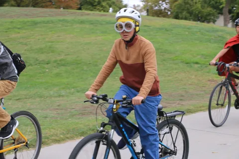A man in a brown jacket rides casually along the path.