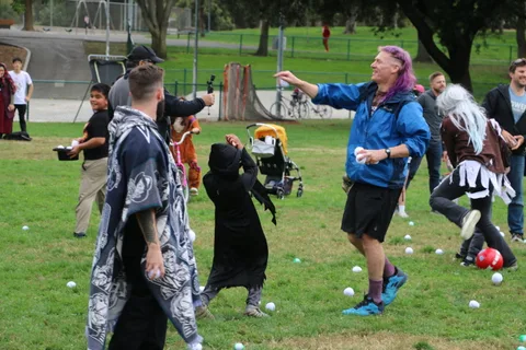 Costumed figures reach for a ball together on the grass.