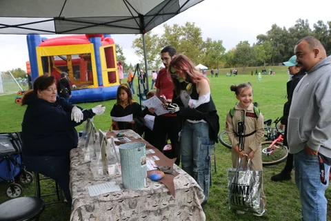 Families gather at an educational booth near the bounce house.