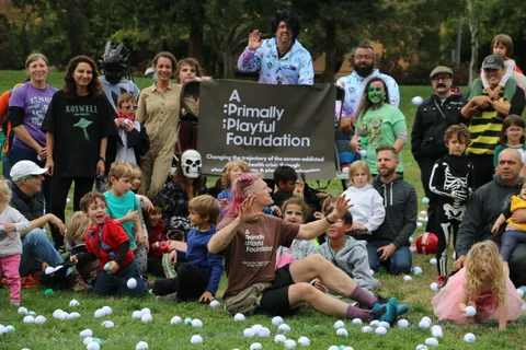 A large group of costumed adults and children pose together in front of a foundation banner.